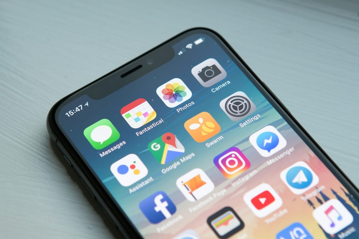 A smartphone on a dark desk, its screen crowded with notifications